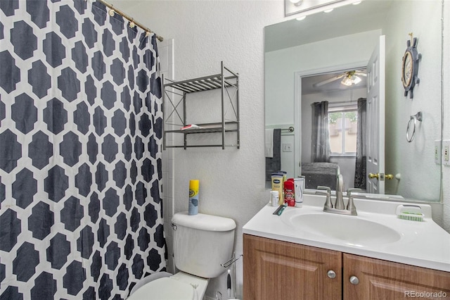 bathroom with ceiling fan, vanity, walk in shower, and toilet