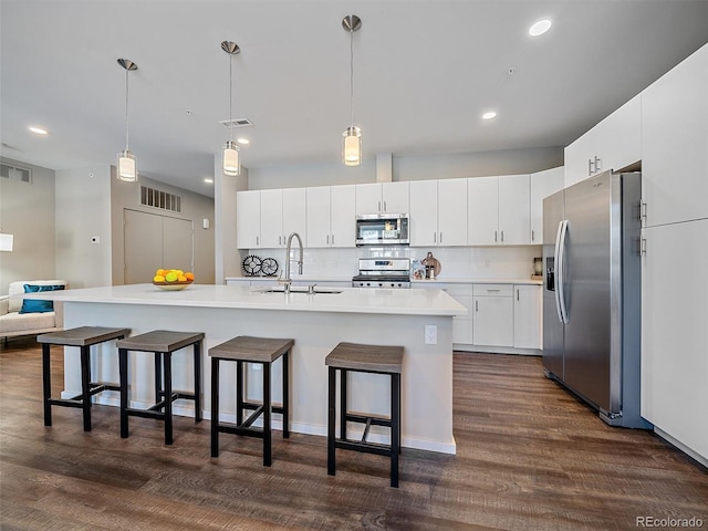 kitchen with white cabinetry, an island with sink, hanging light fixtures, and appliances with stainless steel finishes