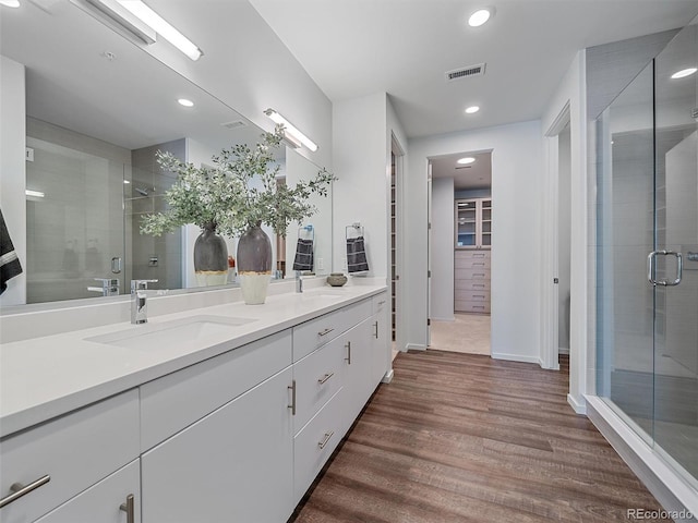 bathroom with hardwood / wood-style floors, vanity, and an enclosed shower