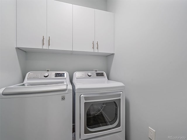 washroom with washing machine and clothes dryer and cabinets