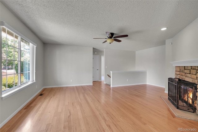 10116 Quivas St, Thornton, CO 80260 - unfurnished living room with light wood finished floors, a ceiling fan, a textured ceiling, and a stone fireplace