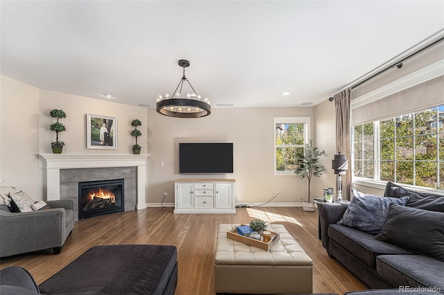 living room featuring a notable chandelier, a fireplace, and light hardwood / wood-style flooring