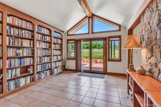 doorway with light tile patterned floors, built in shelves, lofted ceiling with beams, and rail lighting