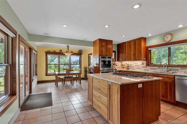 kitchen featuring sink, light stone counters, tasteful backsplash, appliances with stainless steel finishes, and a kitchen island