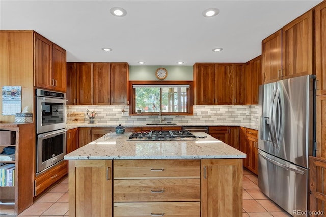 kitchen with stainless steel appliances, light stone countertops, a kitchen island, and light tile patterned floors