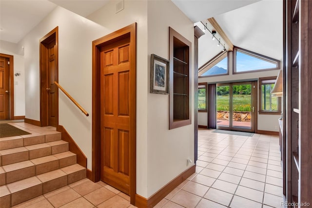 entryway featuring light tile patterned floors, track lighting, and lofted ceiling with beams