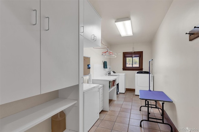 clothes washing area featuring cabinets, washing machine and dryer, and light tile patterned flooring