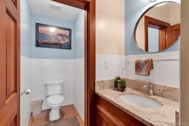 bathroom with tile walls, vanity, tile patterned floors, and toilet