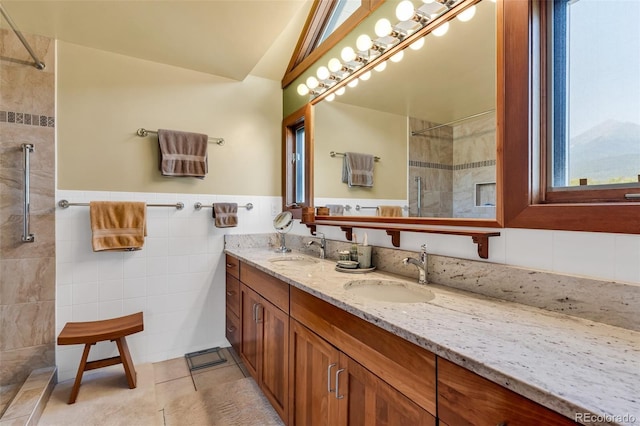 bathroom with tile walls, vanity, tile patterned floors, and tiled shower