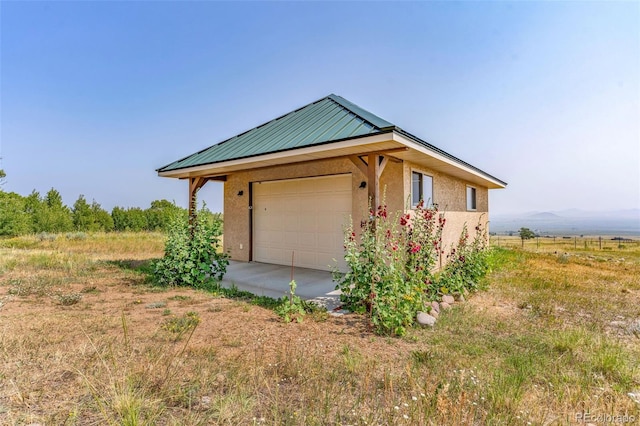 exterior space with a garage and a rural view