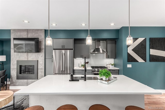 4922 Lowell Blvd Unit 2, Denver, CO 80221 - kitchen featuring appliances with stainless steel finishes, wall chimney exhaust hood, a kitchen breakfast bar, light countertops, and hanging light fixtures