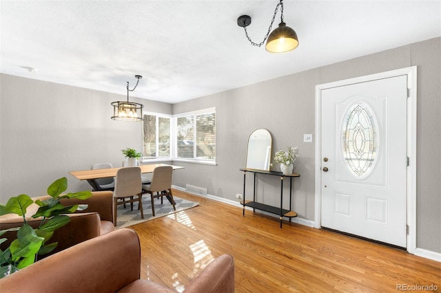 entryway with light hardwood / wood-style flooring and a chandelier