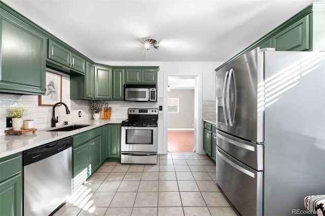 kitchen with stainless steel appliances, sink, light tile patterned floors, and green cabinetry