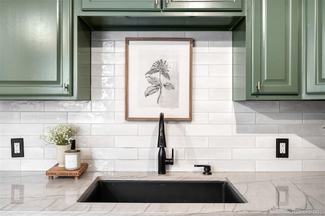 room details featuring light stone counters, green cabinetry, and sink