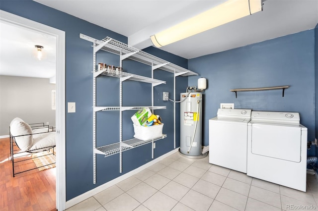 laundry room with washing machine and clothes dryer, electric water heater, and light tile patterned floors