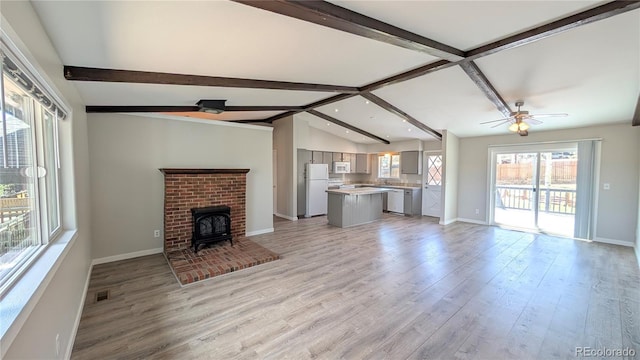 720 Northwoods Dr W, Woodland Park, CO 80863 - unfurnished living room with a healthy amount of sunlight, baseboards, a wood stove, and light wood finished floors