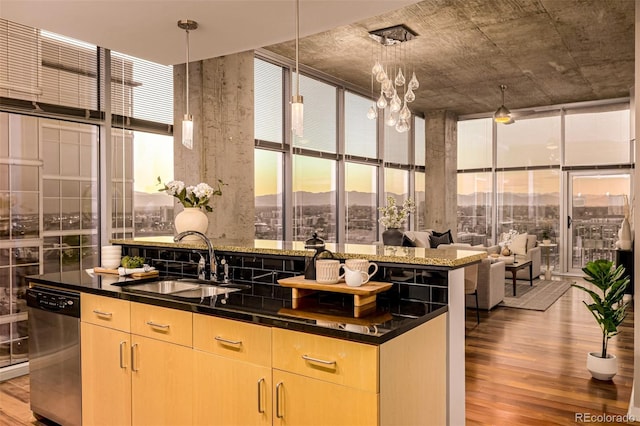 kitchen featuring light brown cabinetry, expansive windows, a sink, wood finished floors, and dishwasher