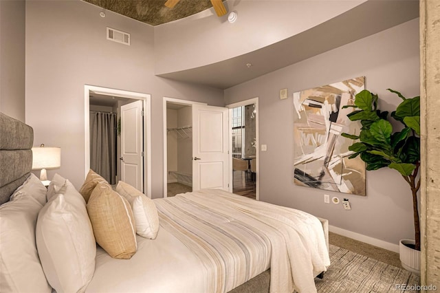 bedroom with carpet floors, visible vents, a spacious closet, and baseboards