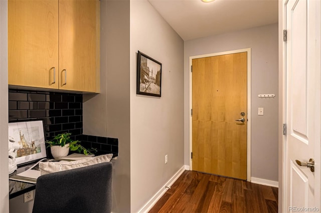 doorway to outside featuring baseboards and dark wood-type flooring