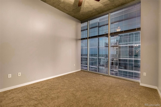 unfurnished room featuring carpet, floor to ceiling windows, ceiling fan, and baseboards