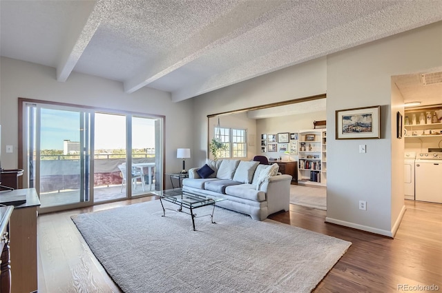 living room with beamed ceiling, a textured ceiling, hardwood / wood-style flooring, and washing machine and clothes dryer