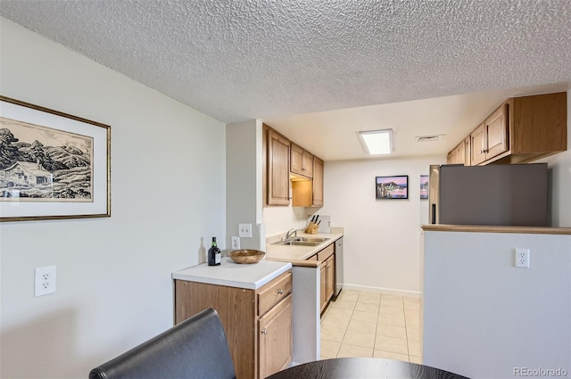 kitchen with appliances with stainless steel finishes, a textured ceiling, light tile patterned floors, and sink