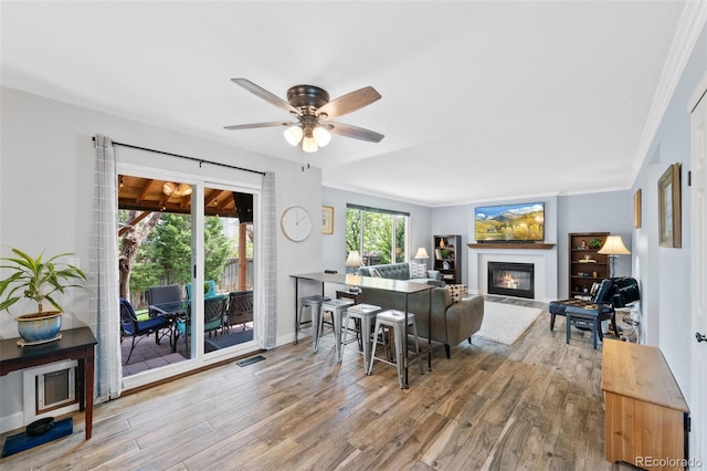 10512 Hyacinth St, Highlands Ranch, CO 80129 - living area featuring a glass covered fireplace, crown molding, a ceiling fan, and wood finished floors