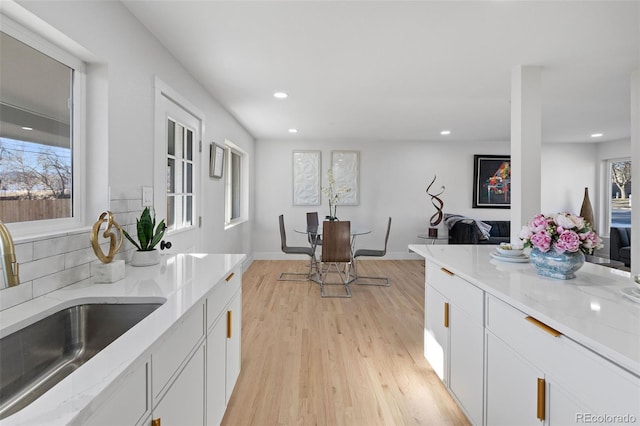 kitchen featuring light stone counters, white cabinets, light hardwood / wood-style flooring, and sink