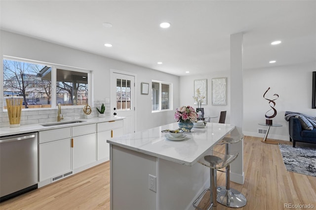 kitchen featuring dishwasher, a center island, sink, light hardwood / wood-style flooring, and white cabinetry