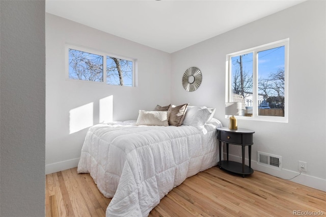 bedroom with multiple windows and hardwood / wood-style flooring