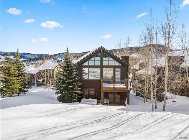 snow covered rear of property featuring a mountain view