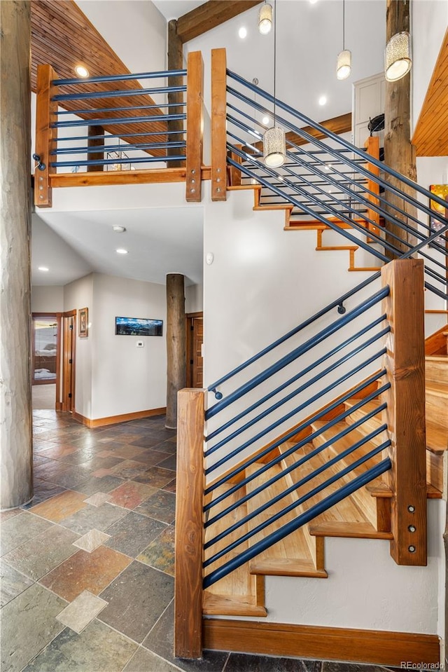 staircase with stone tile flooring, recessed lighting, baseboards, and a towering ceiling