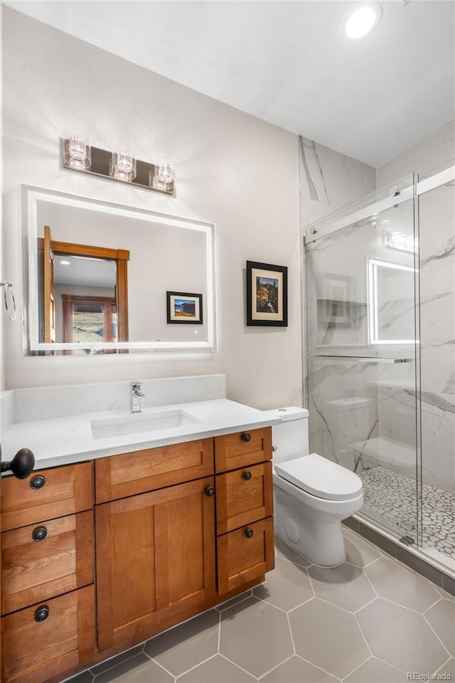 bathroom with a marble finish shower, tile patterned floors, toilet, and vanity