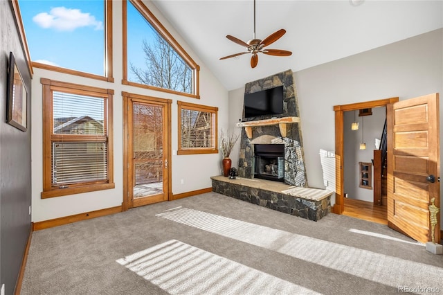 carpeted living area with baseboards, high vaulted ceiling, a stone fireplace, and a ceiling fan