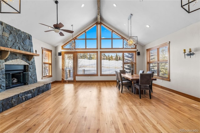 dining space with hardwood / wood-style floors, a fireplace, and high vaulted ceiling