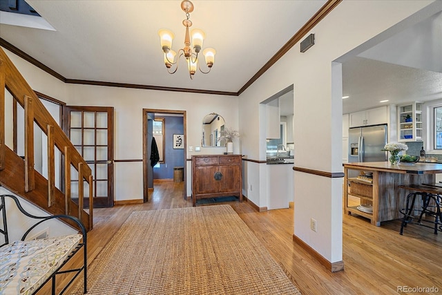 entrance foyer featuring crown molding, sink, light hardwood / wood-style floors, and a notable chandelier