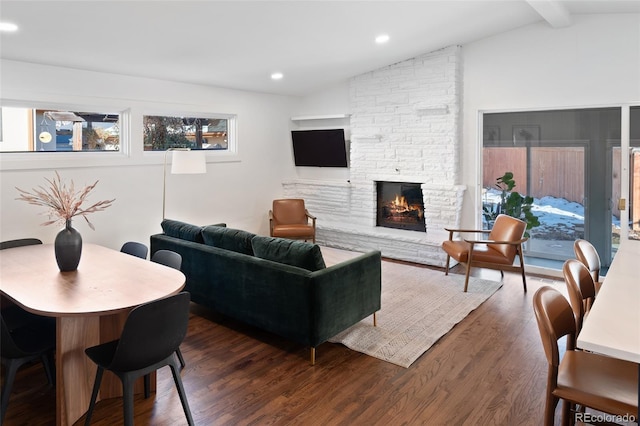 living room featuring dark wood-type flooring, lofted ceiling with beams, and a fireplace