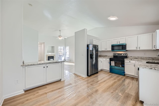 kitchen with black electric range oven, a tiled fireplace, white cabinets, a sink, and stainless steel fridge with ice dispenser