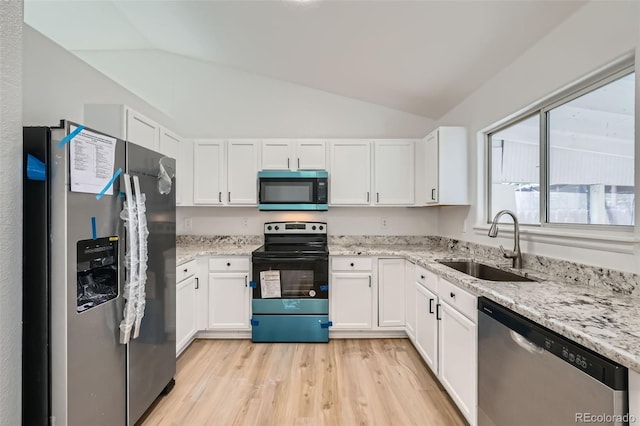 kitchen featuring lofted ceiling, stainless steel appliances, a sink, white cabinets, and light wood finished floors