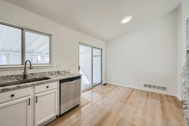 kitchen featuring visible vents, white cabinets, dishwasher, vaulted ceiling, and a sink