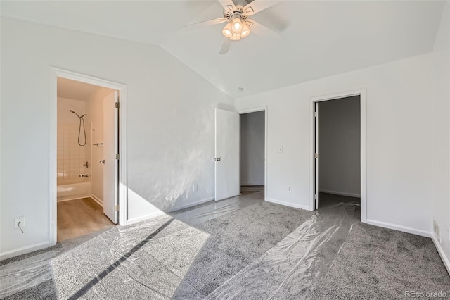 unfurnished bedroom featuring vaulted ceiling, a spacious closet, ensuite bathroom, and baseboards