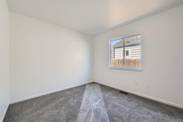 empty room with carpet, visible vents, and baseboards