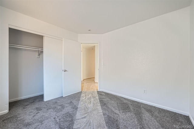 unfurnished bedroom featuring a closet, light colored carpet, and baseboards