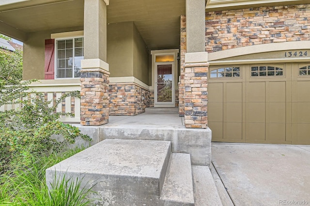 13424 W 64th Pl, Arvada, CO 80004 - doorway to property featuring stone siding, stucco siding, a porch, concrete driveway, and a garage