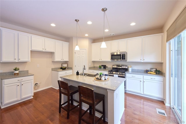 13424 W 64th Pl, Arvada, CO 80004 - kitchen featuring appliances with stainless steel finishes, dark wood-type flooring, white cabinetry, a center island with sink, and recessed lighting