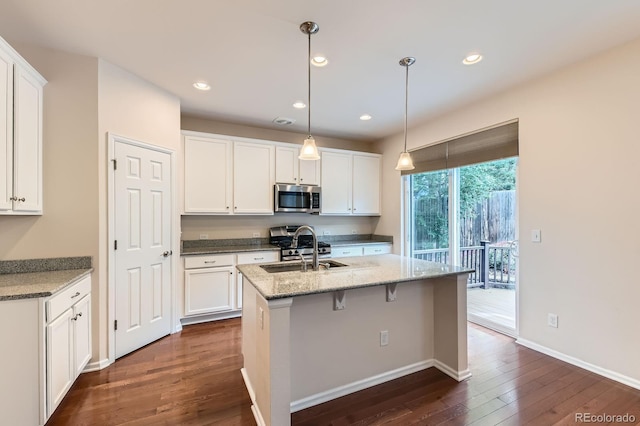 13424 W 64th Pl, Arvada, CO 80004 - kitchen featuring stainless steel appliances, dark wood finished floors, a sink, white cabinets, and a center island with sink