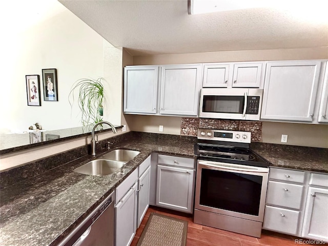 2575 S Syracuse Way Unit F301, Denver, CO 80231 - kitchen featuring appliances with stainless steel finishes, dark stone counters, wood finished floors, and a textured ceiling