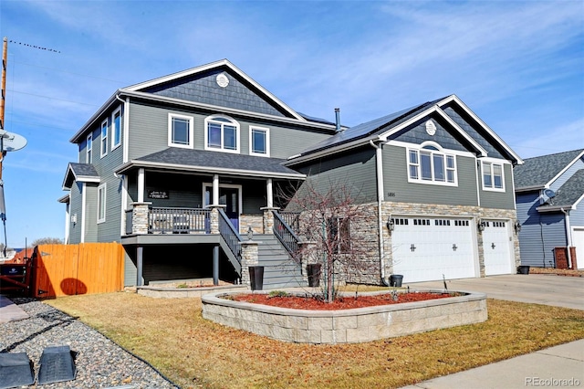 view of front of house with covered porch, an attached garage, driveway, stairway, and stone siding