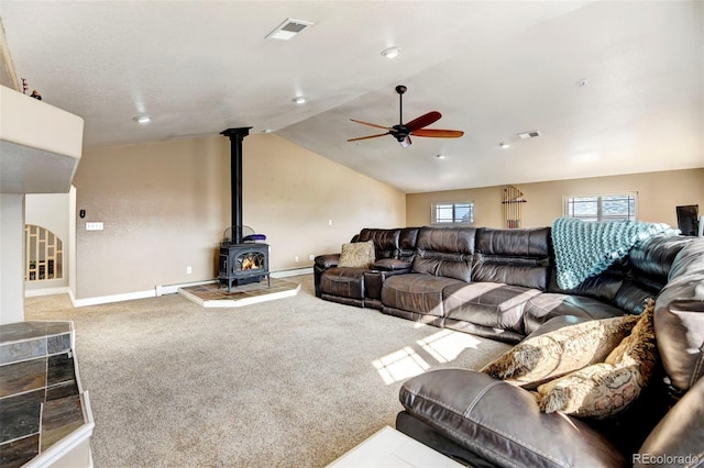 carpeted living area featuring ceiling fan, vaulted ceiling, baseboards, a wood stove, and recessed lighting