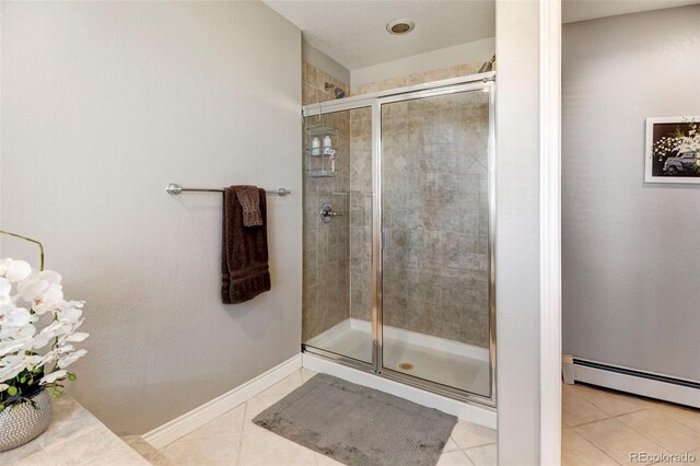 bathroom featuring a stall shower, tile patterned floors, a baseboard heating unit, and baseboards